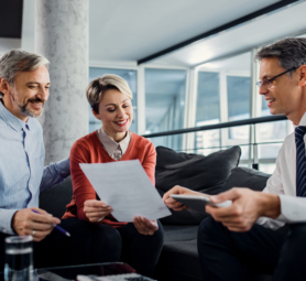 Happy couple analyzing an agreement with their insurance agent during a meeting in the office.