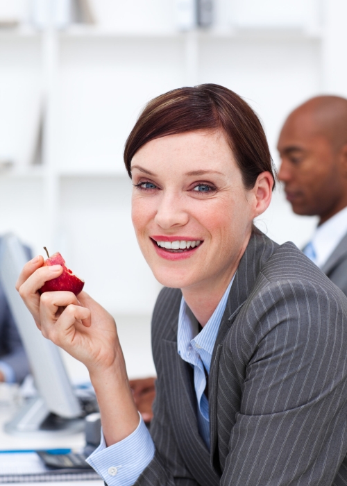 Portrait of a smiling businesswoman eating an apple in the office